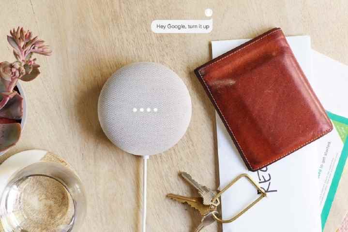Google'ın Nest Mini'si, beyaz, diğer kişisel eşyalarla birlikte masada.