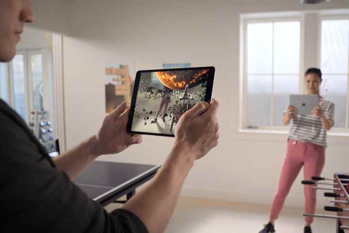 Apple iPad'de artırılmış gerçeklik oyunu oynayan iki kişi.