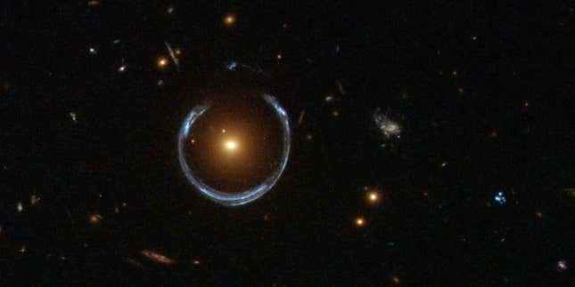 Bir Einstein Halkası, yerçekimsel merceklemenin göze batan bir örneği olan parlak bir kırmızı galaksiyi çevreler.