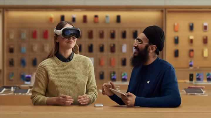 Bir kişi, yanında bir Apple çalışanıyla birlikte bir Apple Store'da Apple Vision Pro karma gerçeklik kulaklığını deniyor.