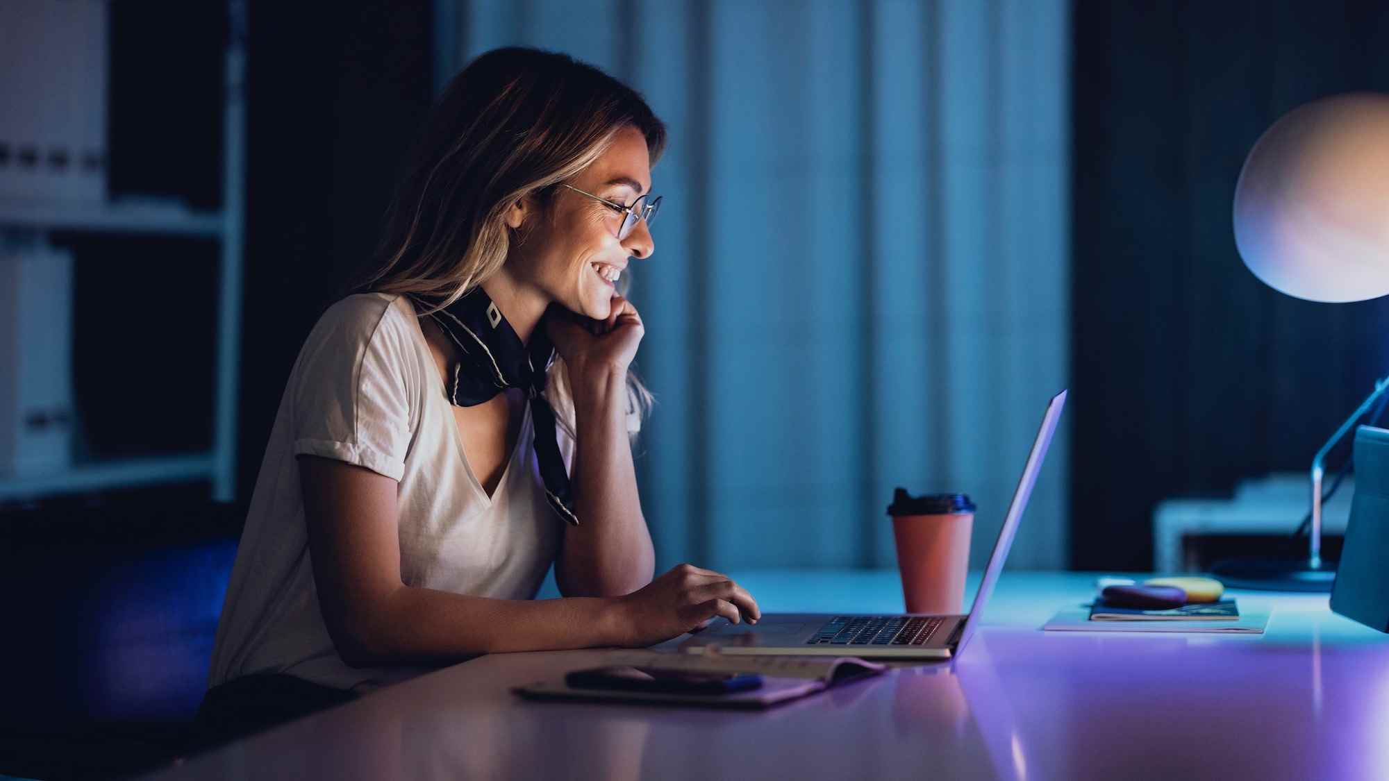 Geceleri içeride dizüstü bilgisayar kullanan genç kadın