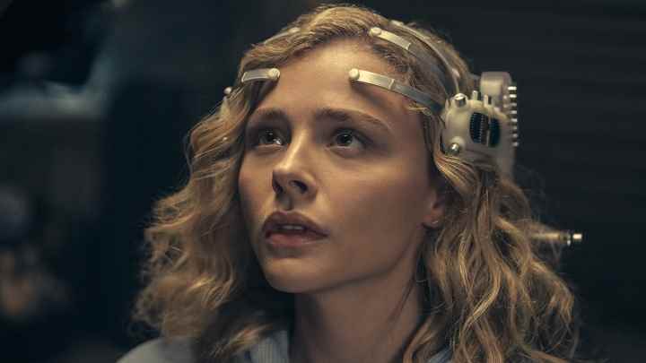 Chloe Grace Moretz, Amazon Prime'da The Peripheral'dan bir sahnede fütüristik bir oyun kulaklığı takıyor.