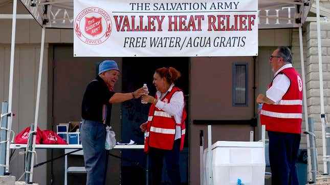 Salvation Army gönüllüsü Francisca Corral, merkez, 11 Temmuz 2023'te Phoenix'te Valley Heat Relief Station'da bir adama su veriyor.