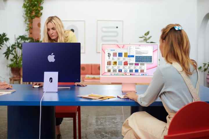 İki kişi bir ofiste bir masanın üzerinde iMac kullanıyor.